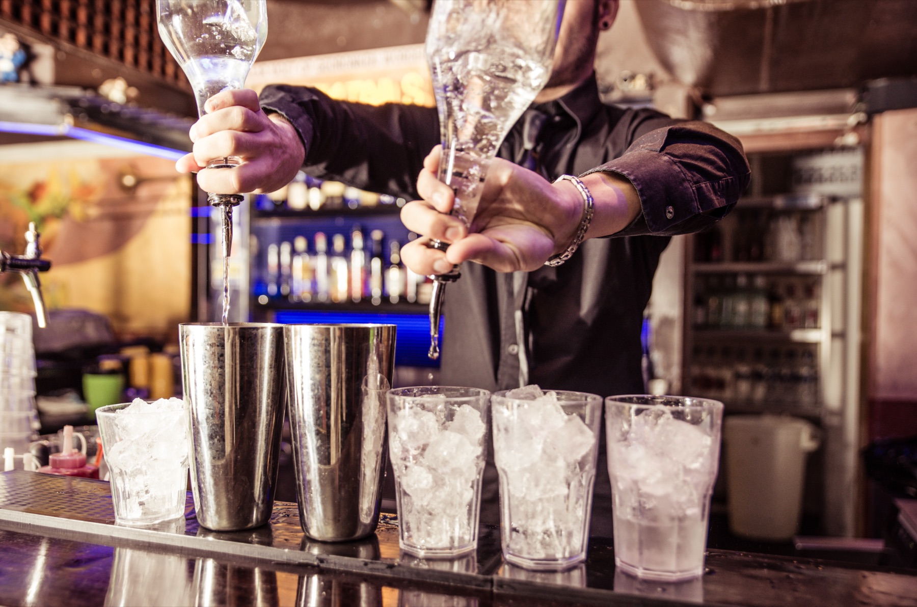 Bartender som häller upp drinkar bakom en bardisk