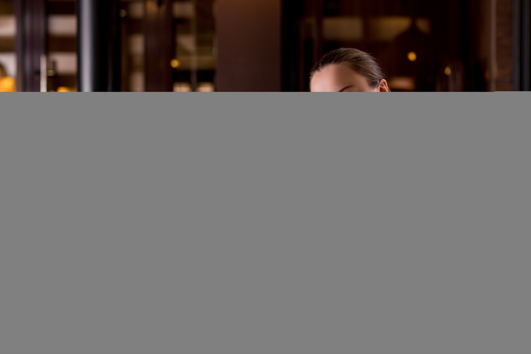 Leende kvinna i randig skjorta som håller upp en svart menypärm i en mörk restaurangmiljö