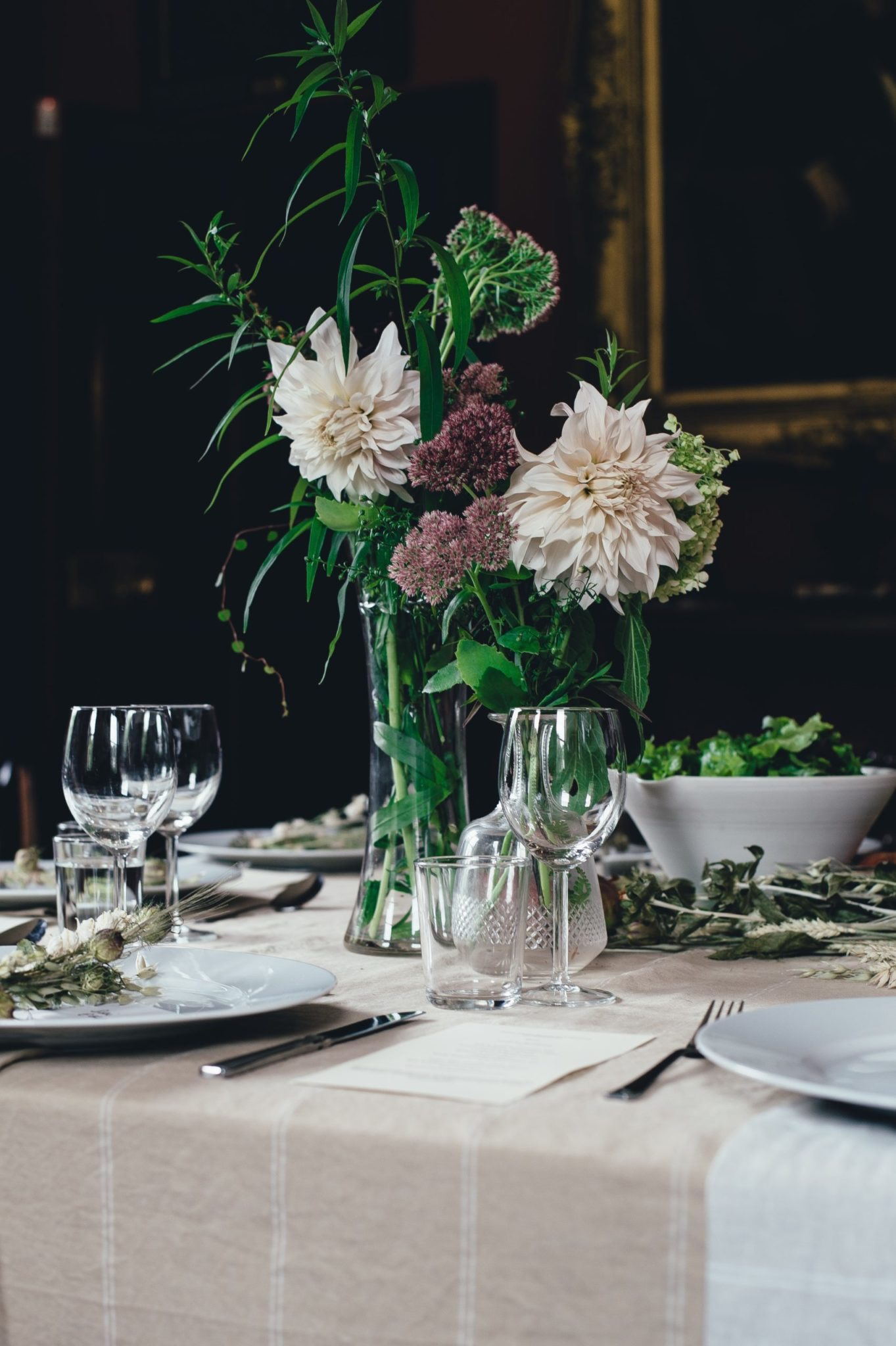 Mörk lokal med dukat bord, glas och vita blommor