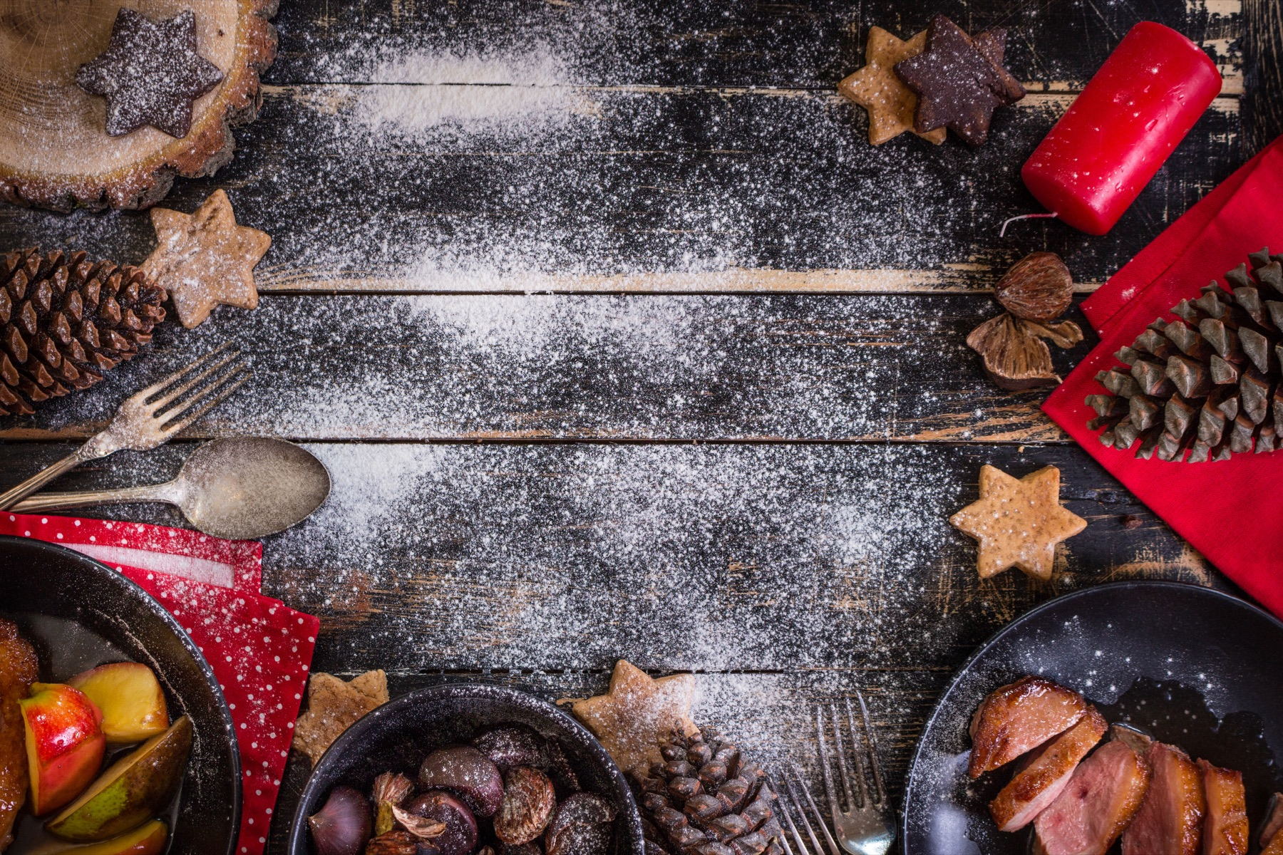 Julmotiv med grankottar, pepparkakor och röda detaljer på mörkt trä