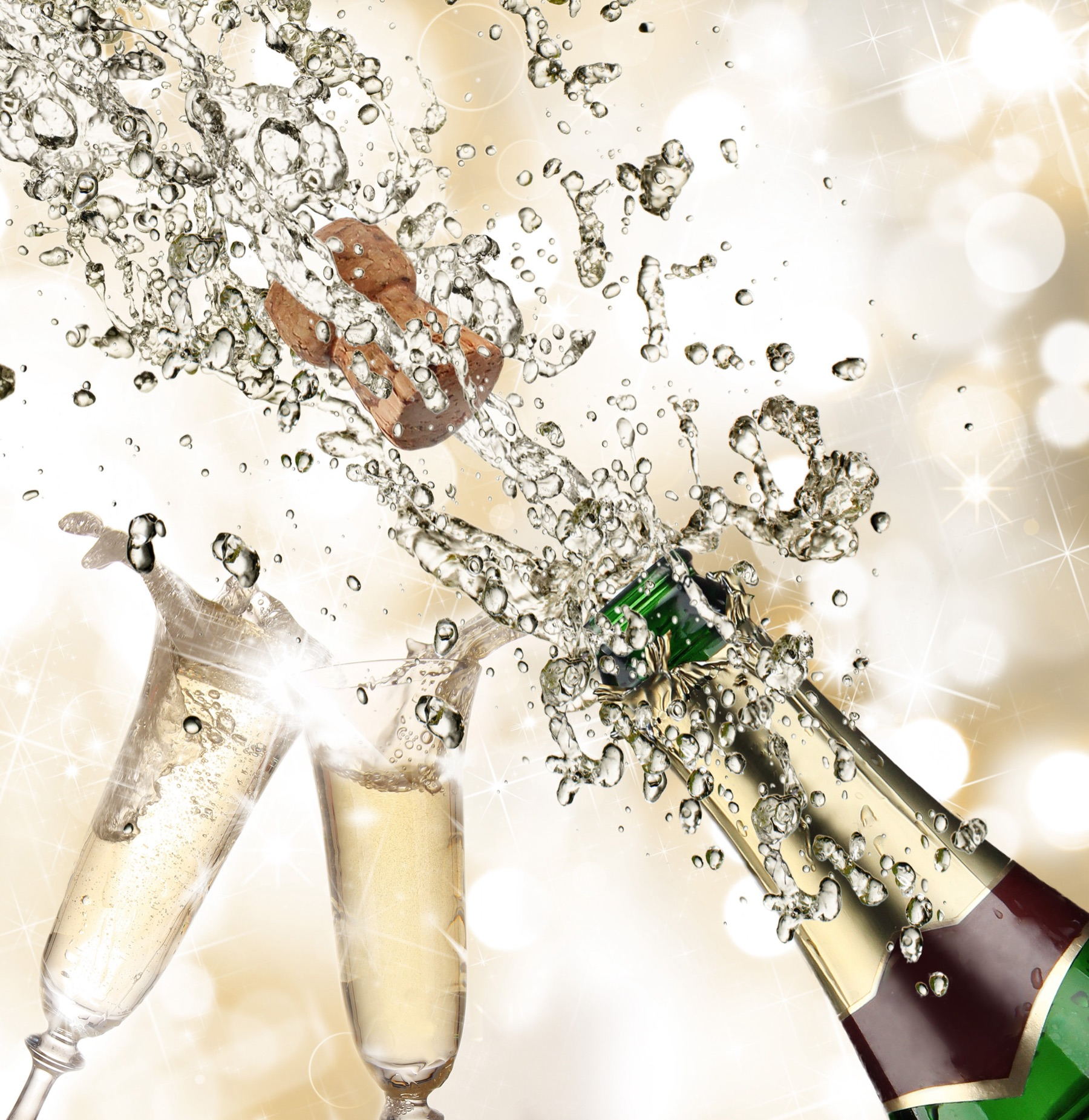 Champagneflaska som poppar bredvid två fyllda champagneglas
